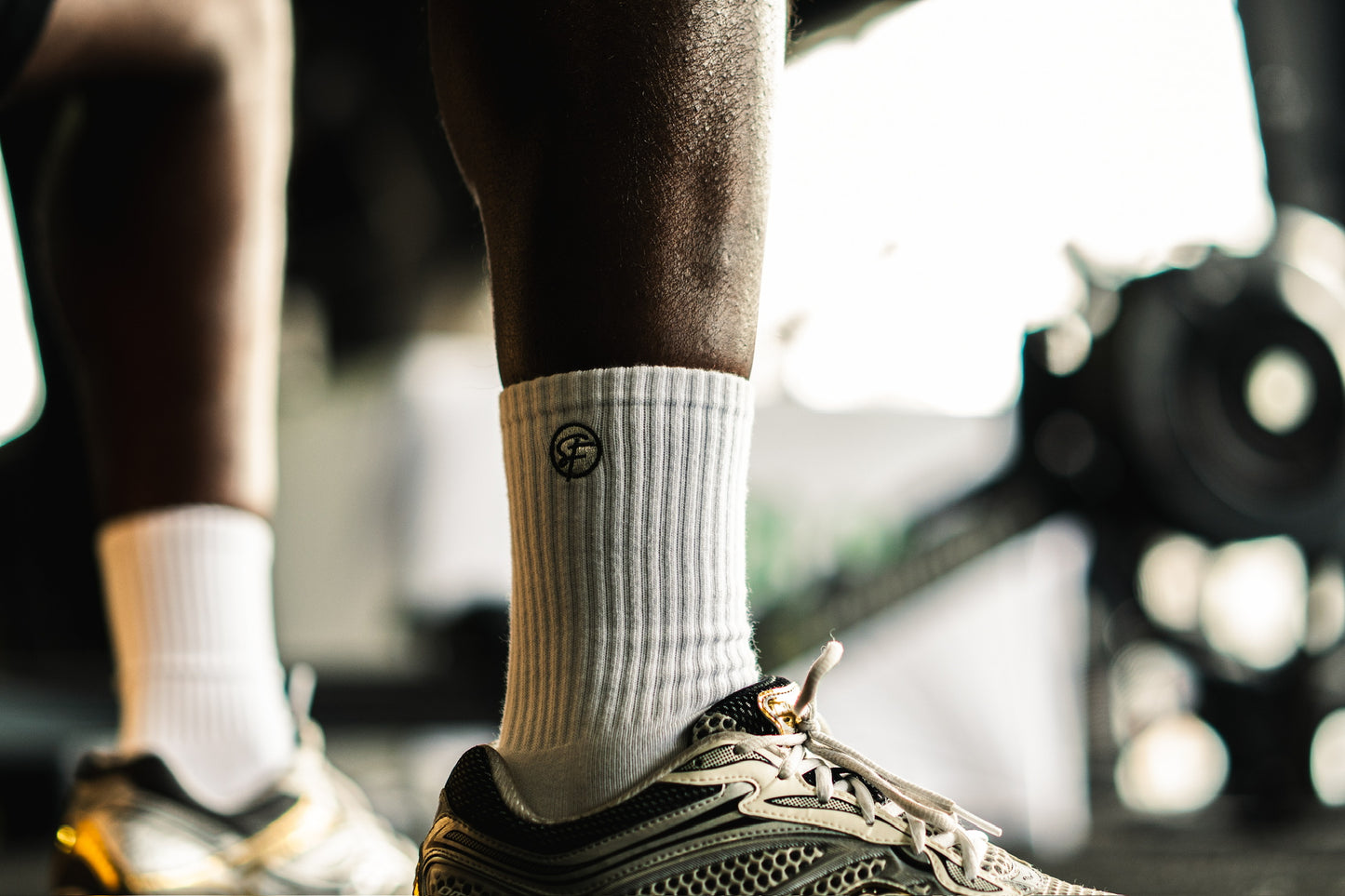 Person wearing white athletic socks with a SickFit logo and black athletic shoes on a blurred background