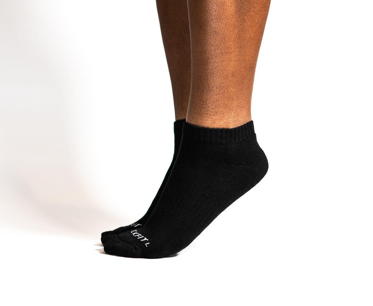Black athletic ankle socks worn by a person on a white background