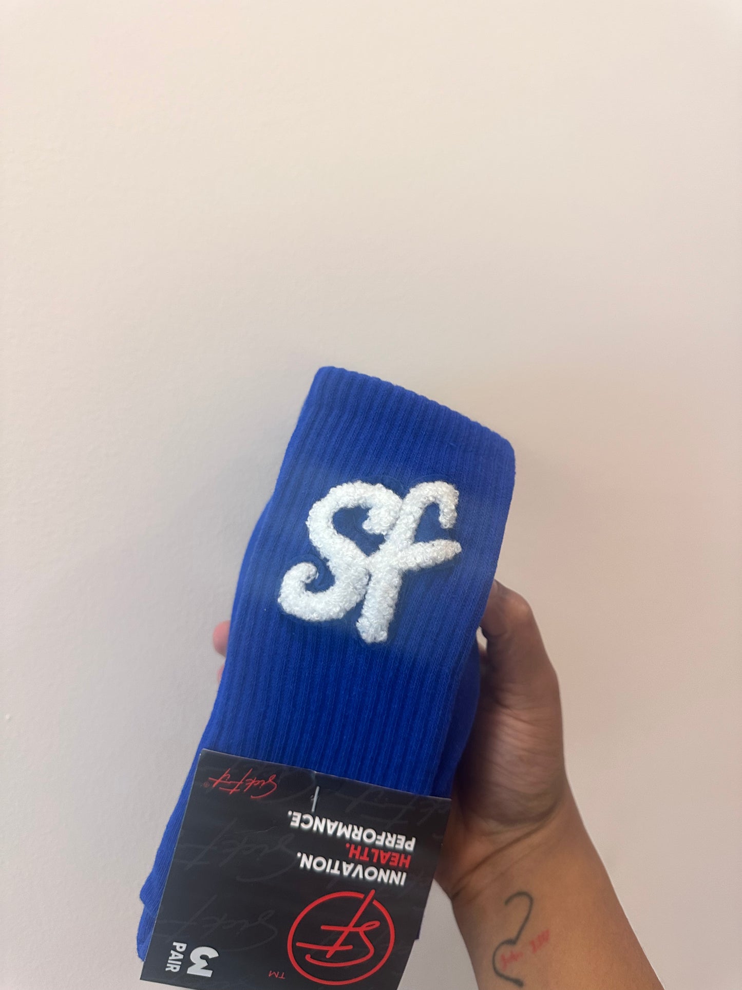Blue crew compression sock with white SickFit logo held against a plain background