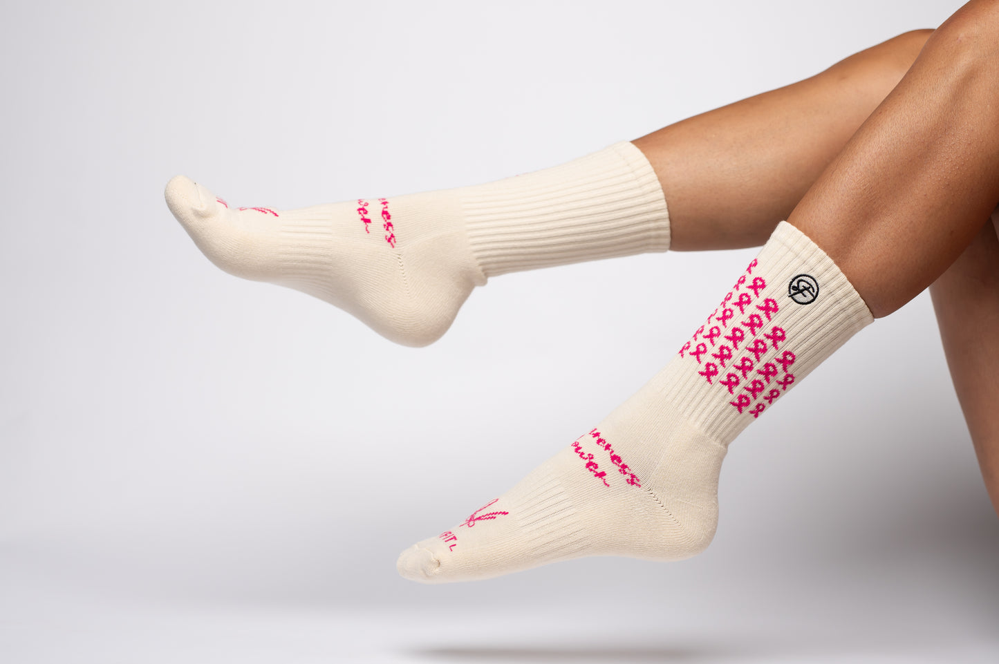 White crew compression socks with pink patterns worn by a person on a light gray background