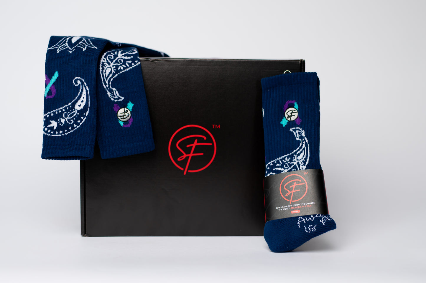 Two pairs of blue crew compression socks with colorful designs on a black box featuring a red logo.