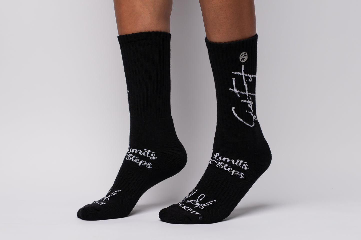 Black crew compression socks with white text worn by a person on a plain background
