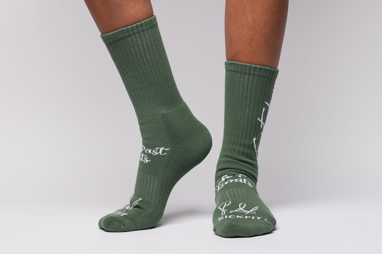 Green crew compression socks with text worn by a person on a light gray background