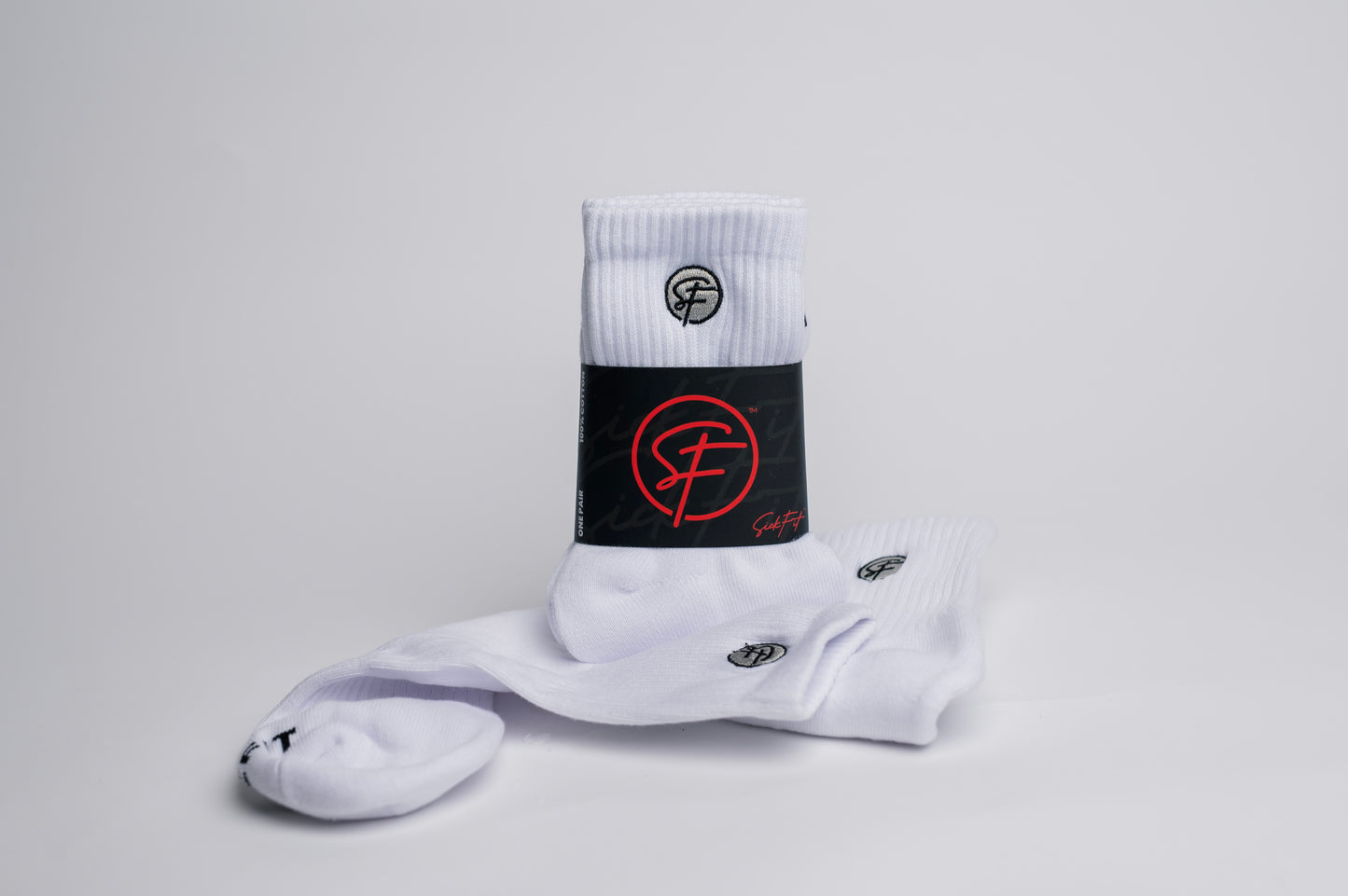 A pair of white SickFit quarter socks with black and red design elements, including the brand's logo in red on the ankle area.