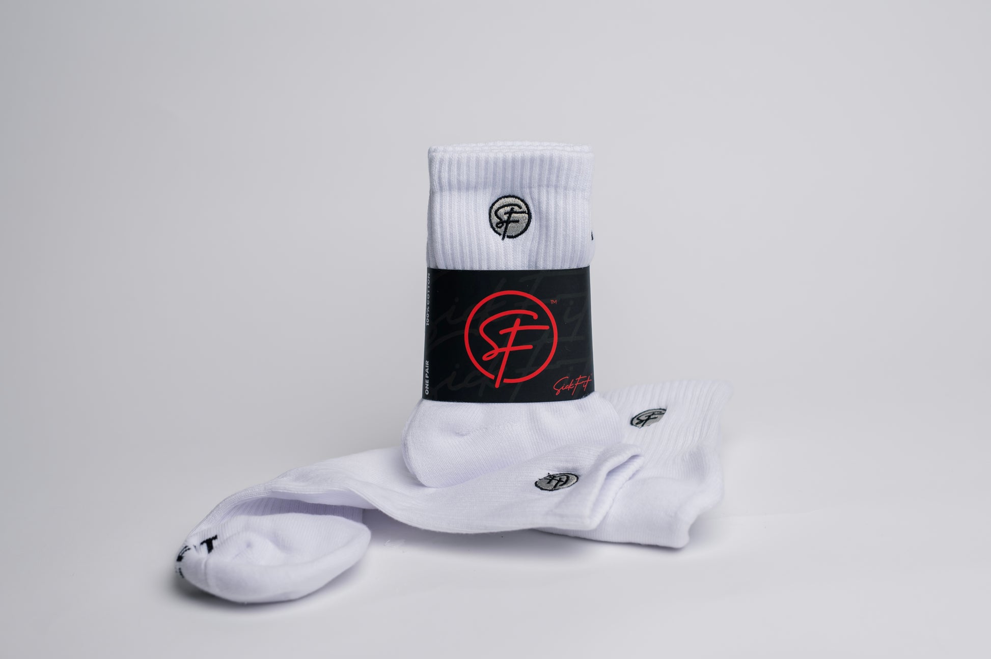 A pair of white SickFit quarter socks with black and red design elements, including the brand's logo in red on the ankle area.