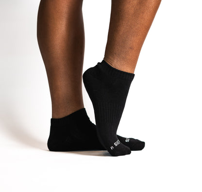 Black ankle socks worn by a person on a white background