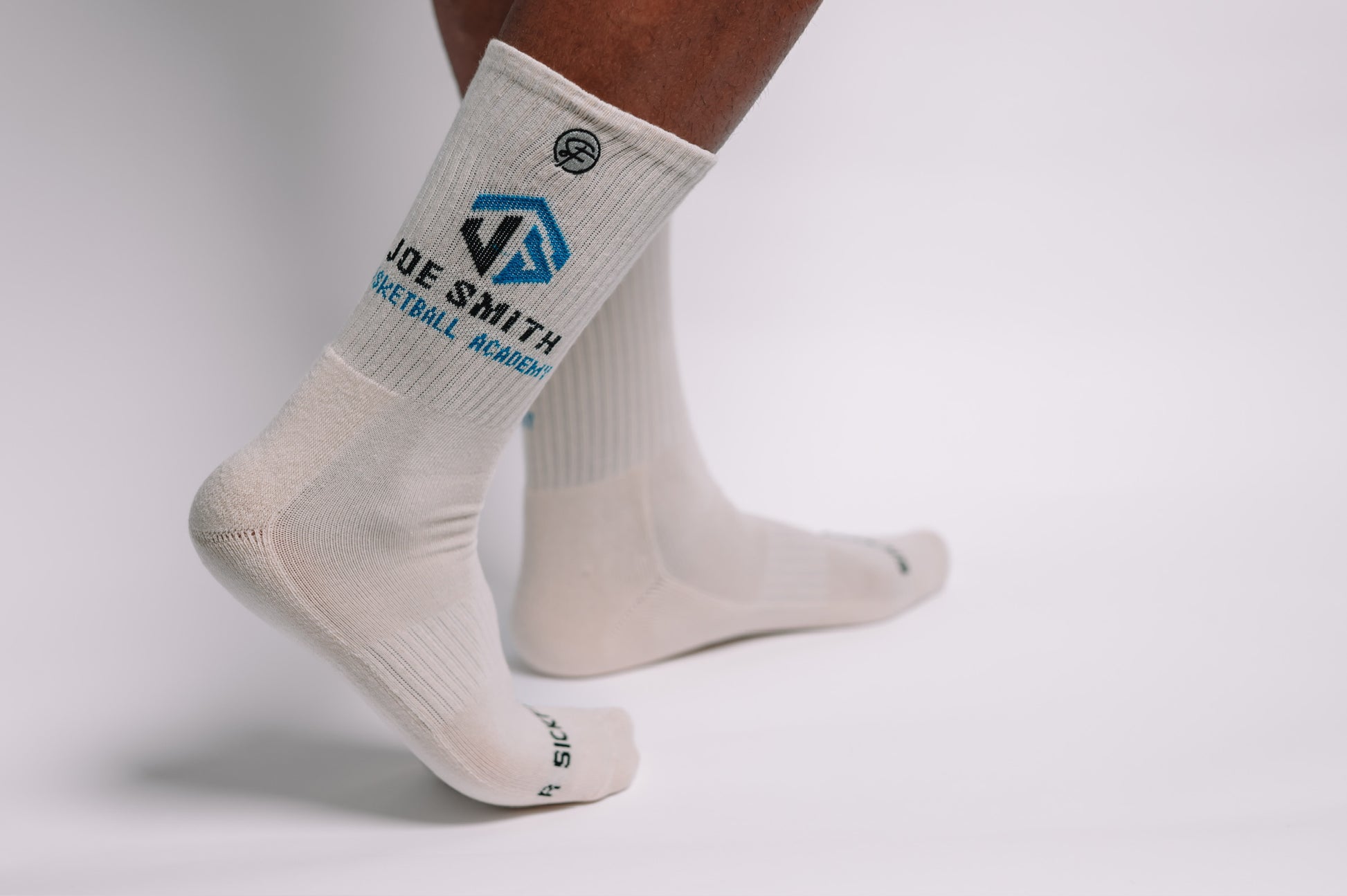 White crew compression socks with a logo on the foot area against a light gray background