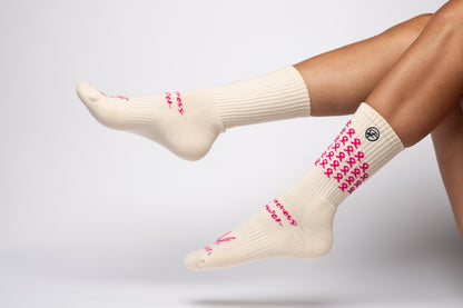 White crew compression socks with pink patterns worn by a person on a light gray background