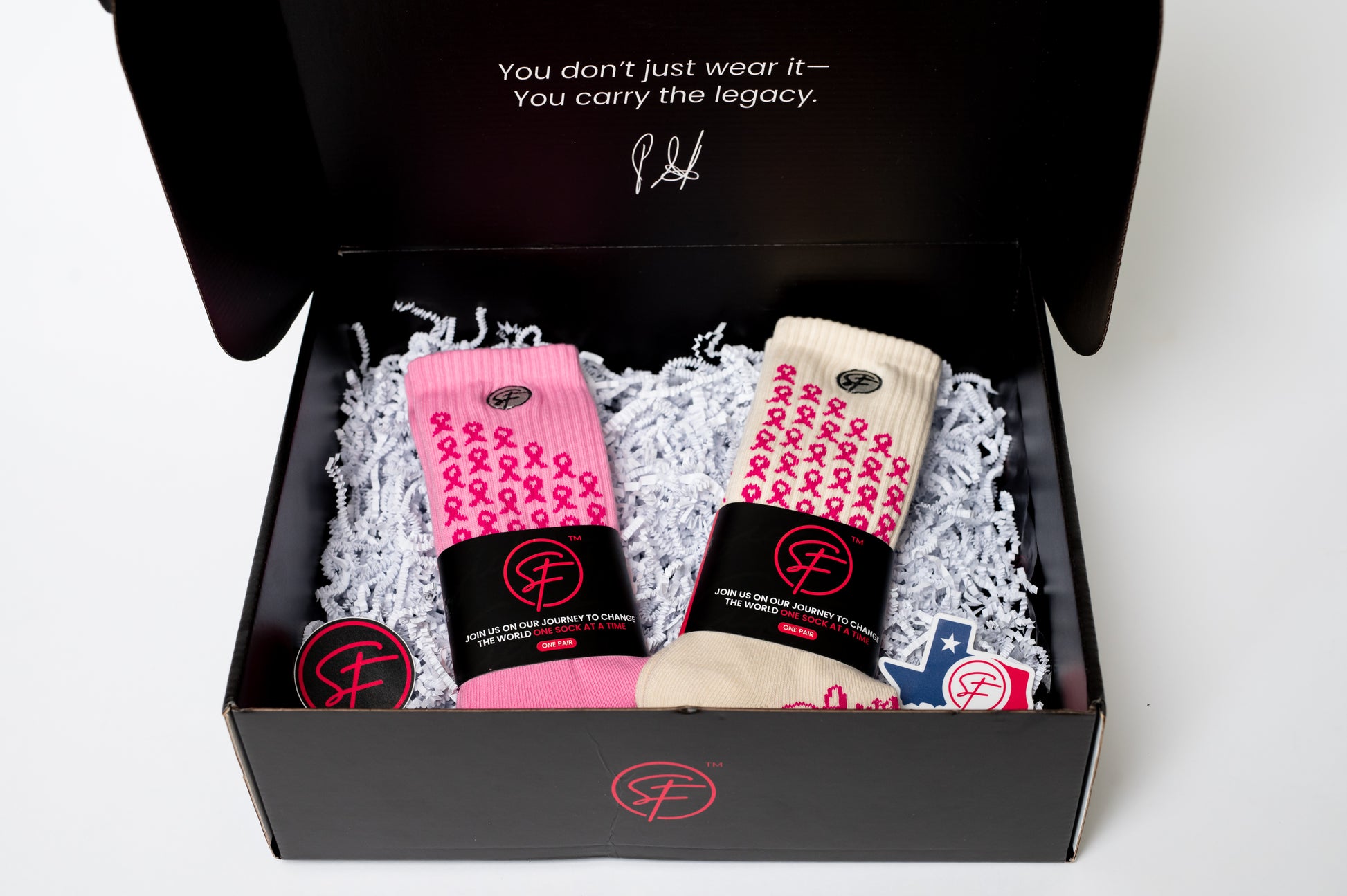 Box of crew compression socks with pink and black design, featuring a message about carrying the legacy.