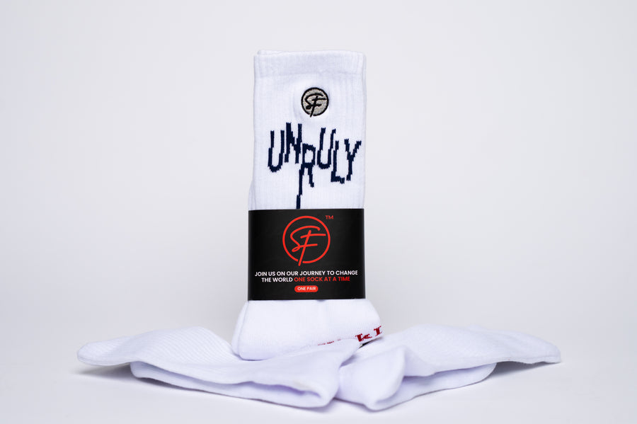 White crew compression socks with 'UNRULY' branding on a light gray background