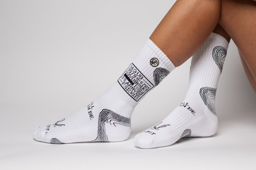 White designer socks with black designs worn by a person on a light gray background