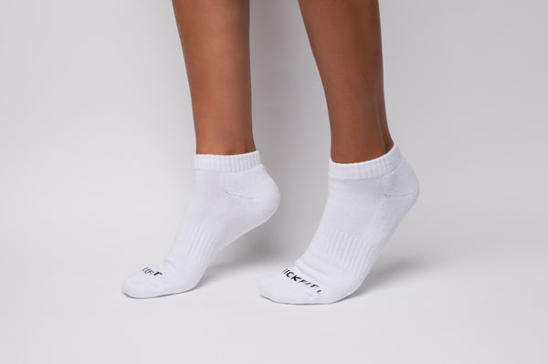 White ankle compression socks worn by a person on a light gray background
