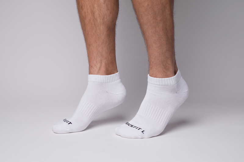 White ankle socks with text on the toes against a neutral background