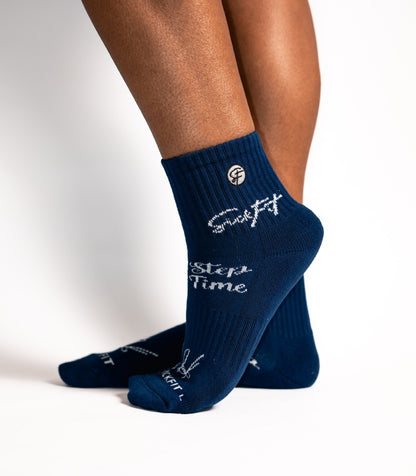 Navy blue calf socks with white text worn by a person on a light gray background